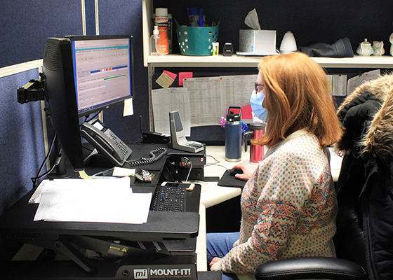 A Shared Ride Dispatcher wears a mask at her work station